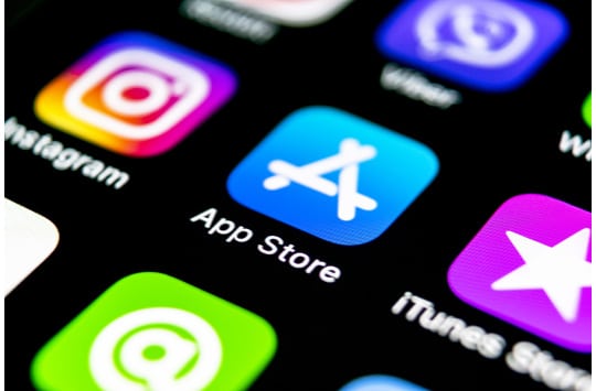 Close-up of smartphone with App Store app featured in the center between Instagram and iTunes Store.