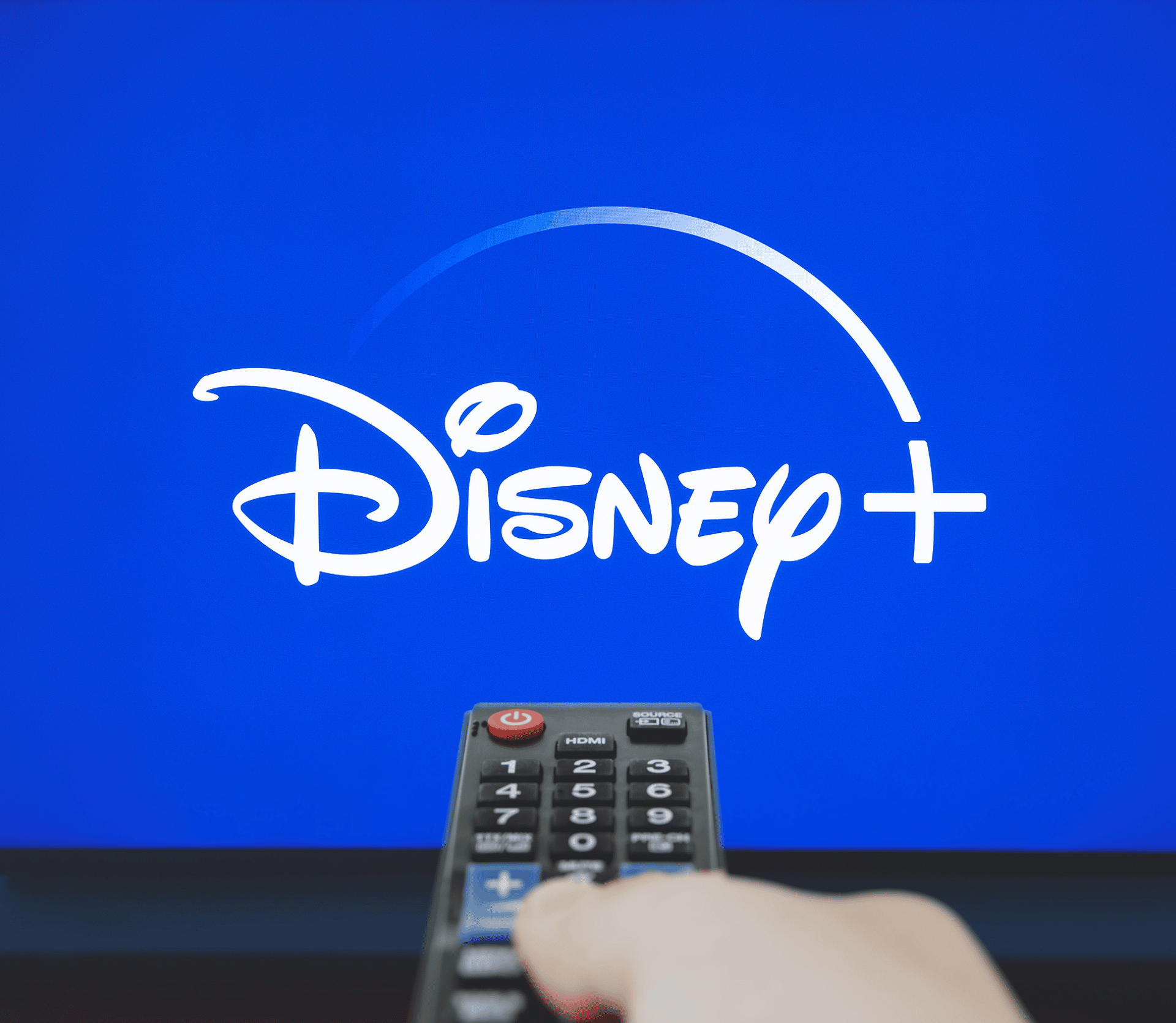 Viewer points remote at Disney+ streaming video subscription service on big screen TV