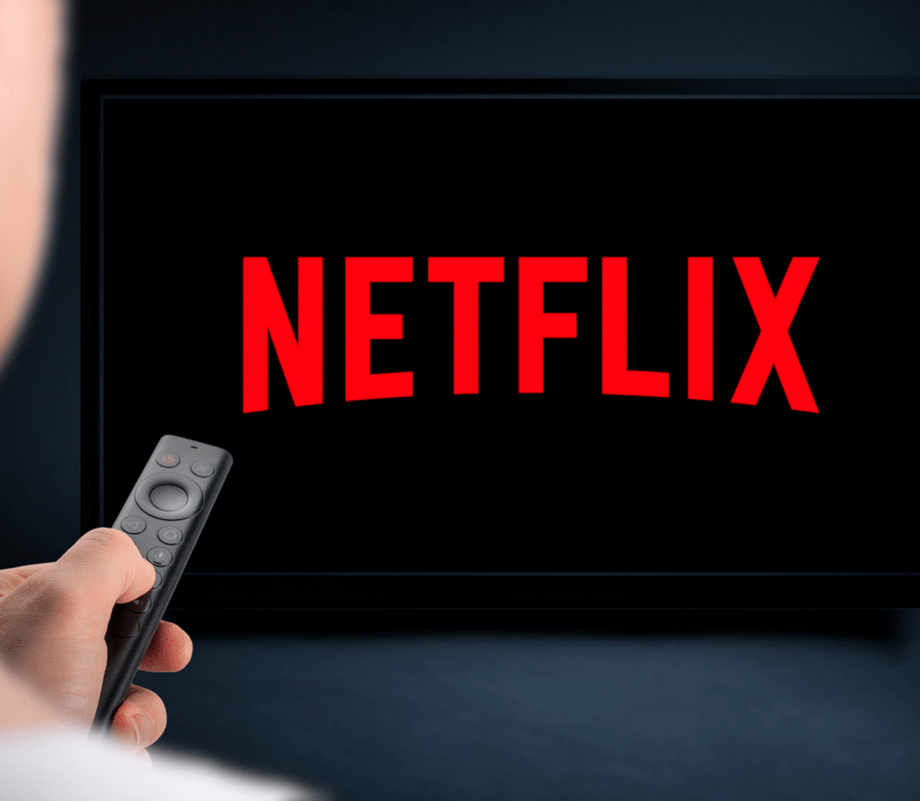 Man with remote watches streaming VOD service Netflix on big screen TV