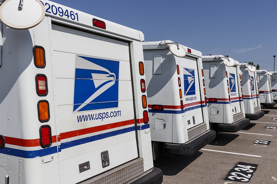 USPS mail trucks lined up in a parking lot
