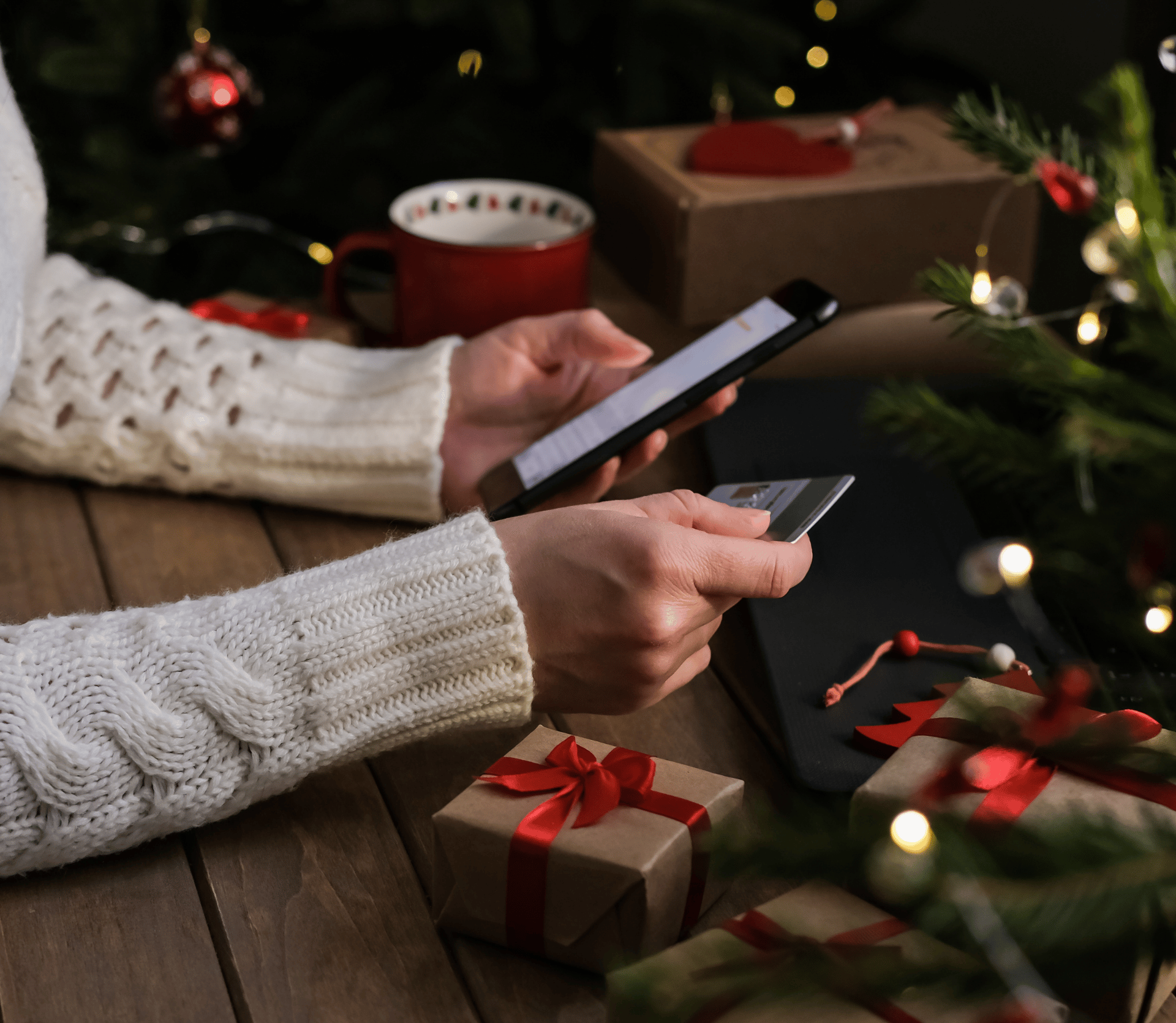 Woman sitting by Christmas tree does holiday shopping online with credit card.