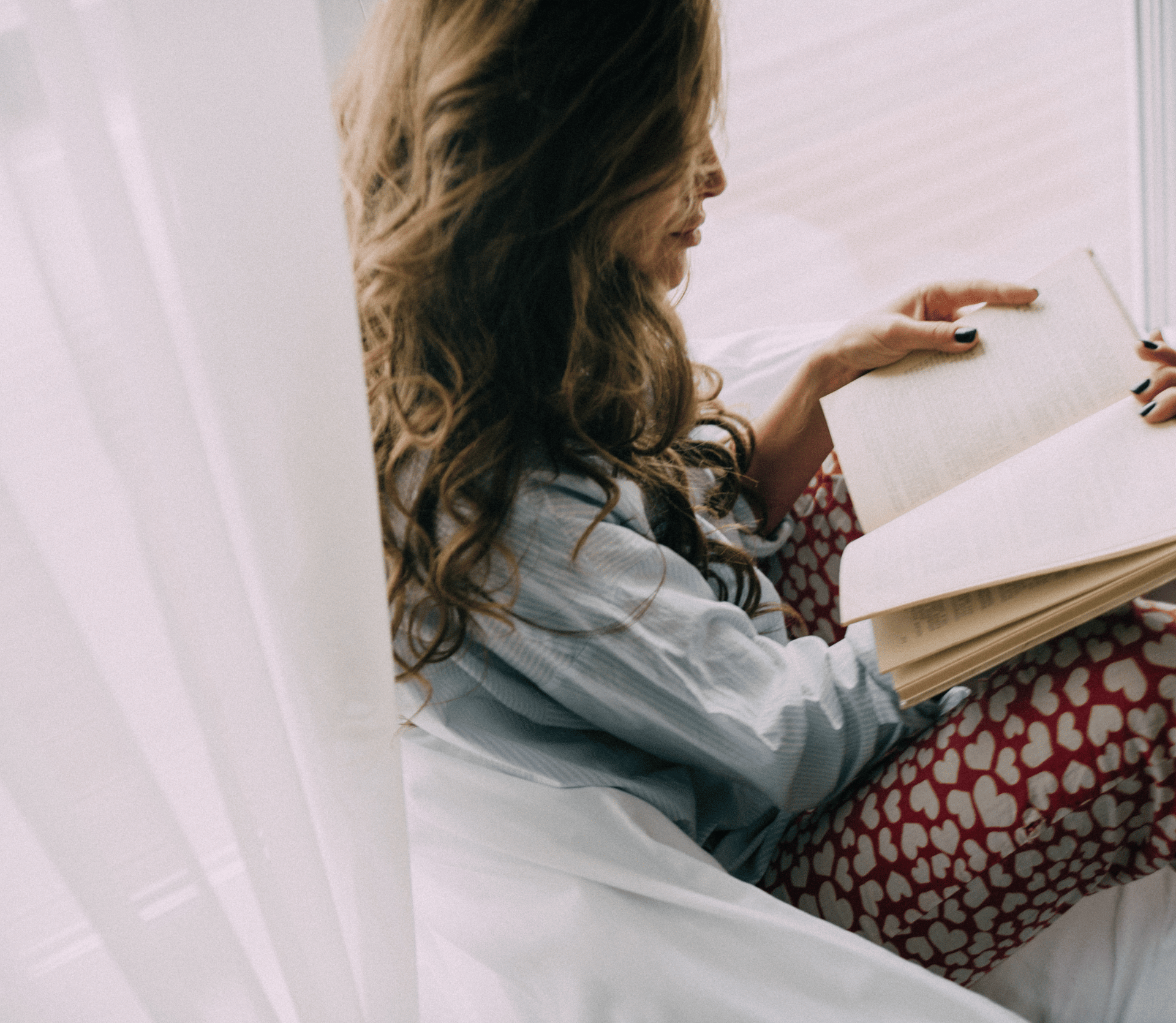 Woman reads romance novel in cozy bed