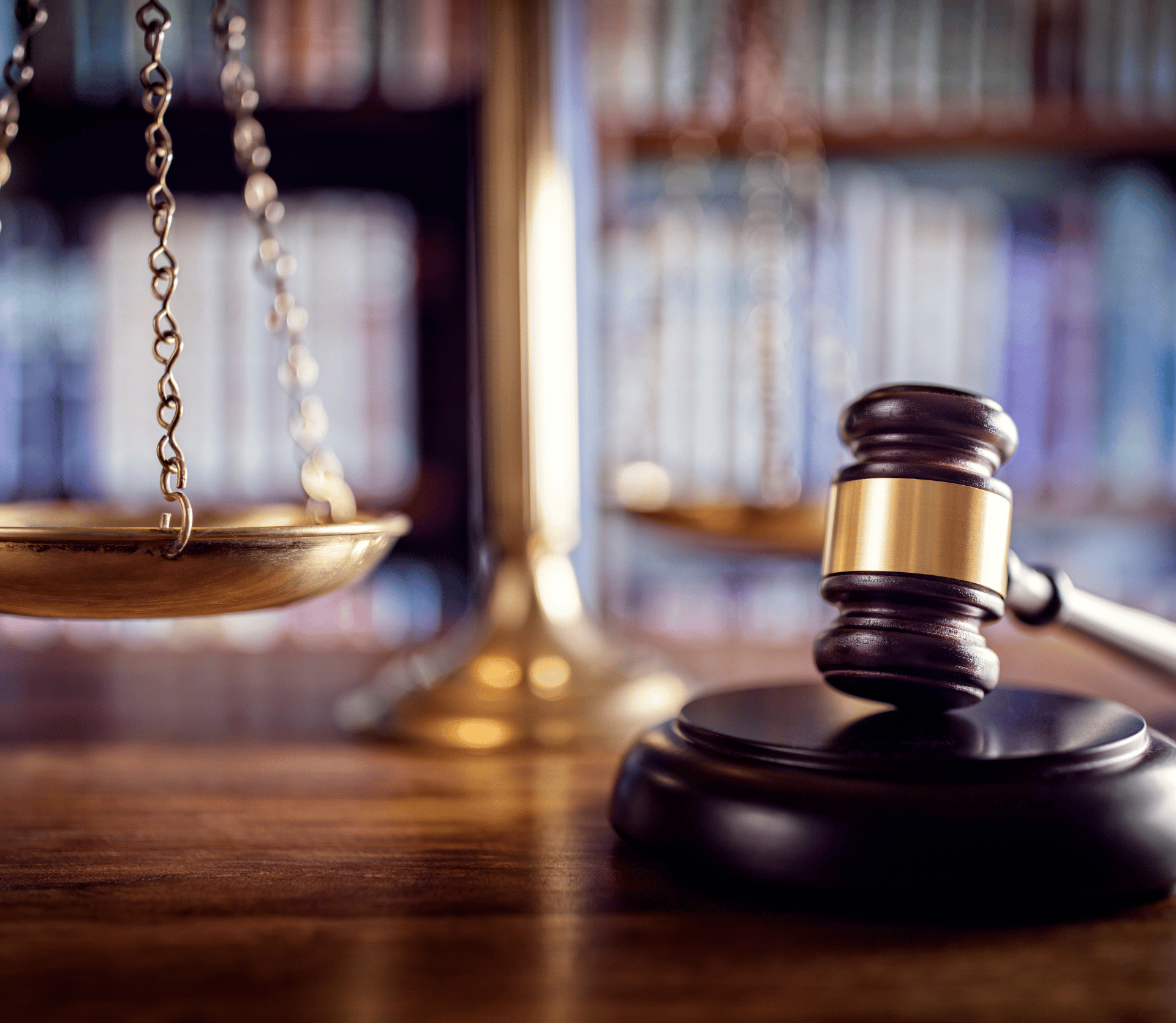 Gavel and scales of justice in front of a library of books, signifying law, justice and compliance with copyright laws