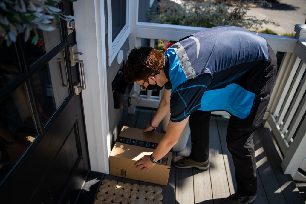 Amazon delivery driver sets package on customer's porch.