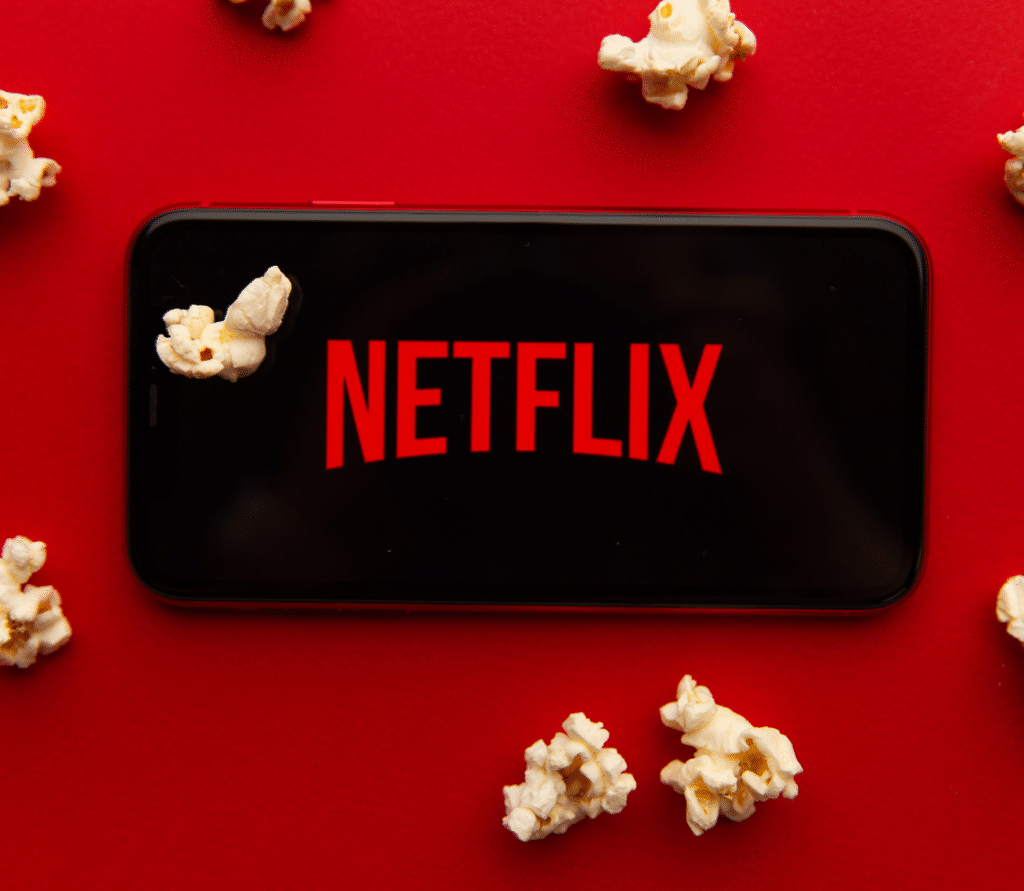 Netflix logo on mobile device on red background with popcorn