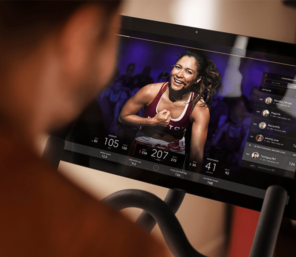 Man sits on Peloton bike watching a live class