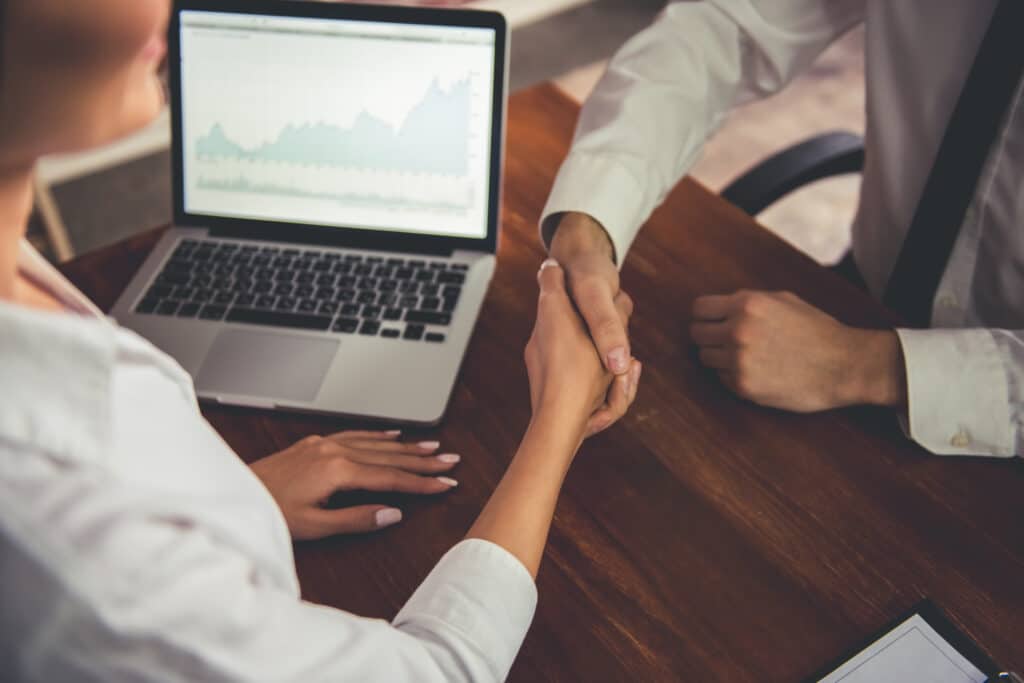 Two people shaking hands across a desk