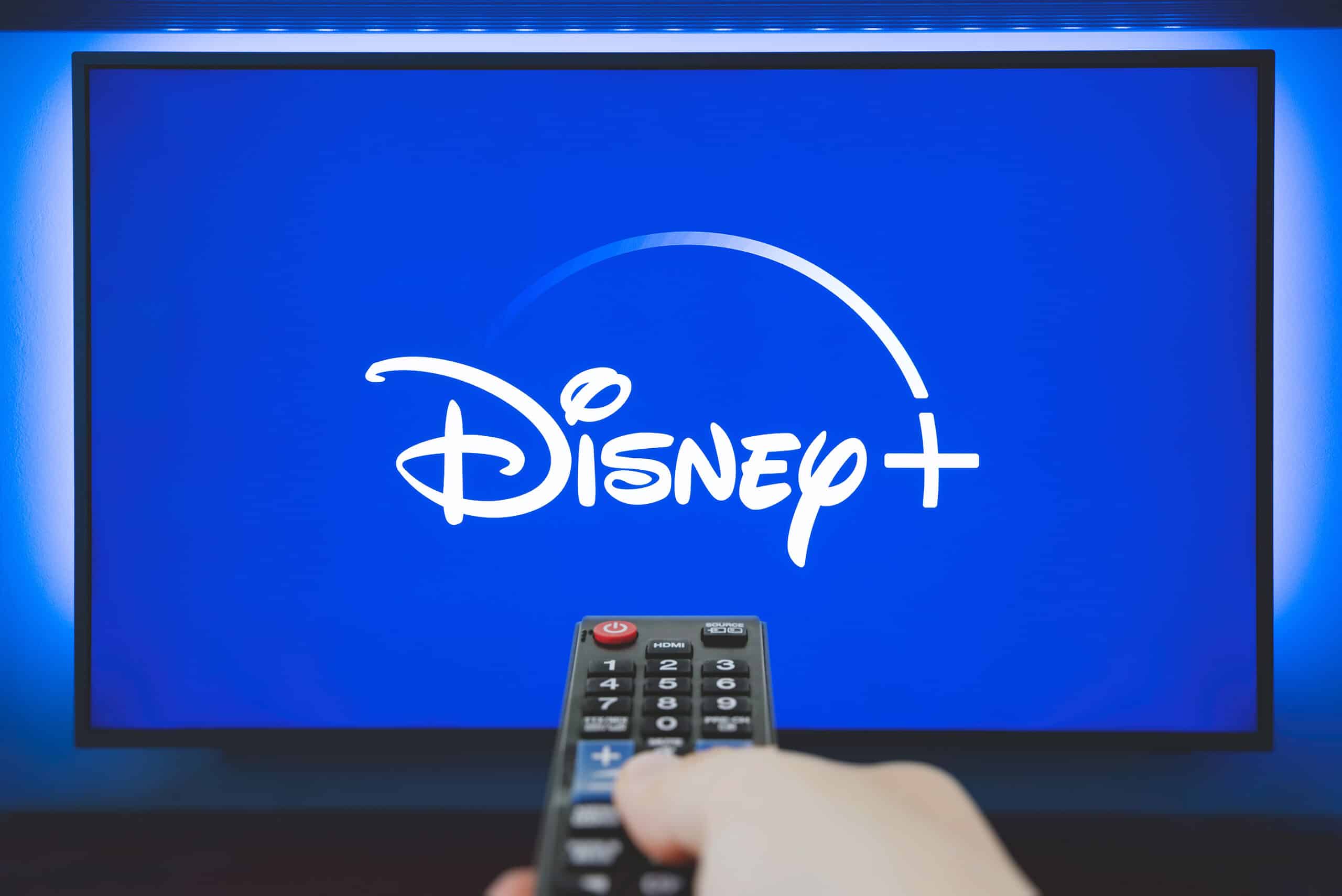 Viewer points remote at Disney+ streaming video subscription service on big screen TV