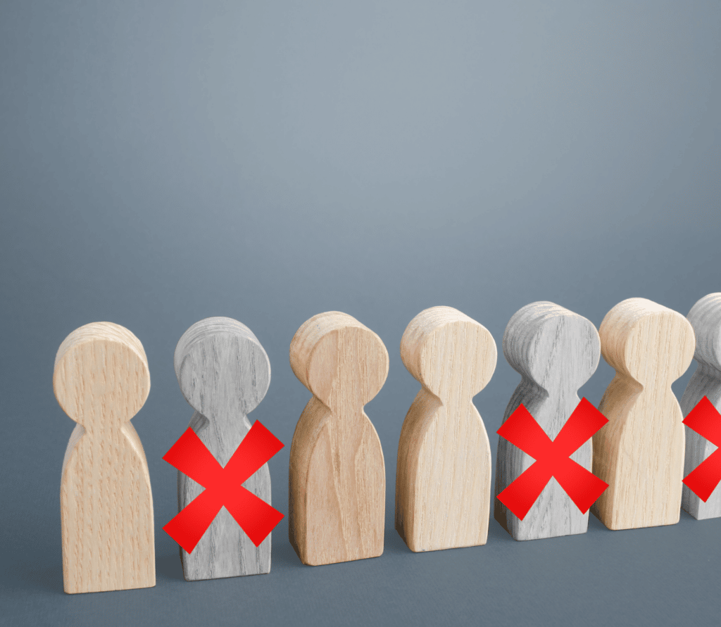 Six wooden people, three with red Xs on them, representing staffing cuts