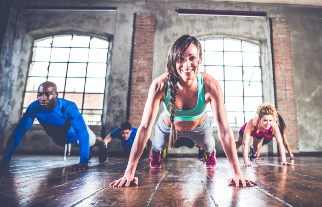 Three athletes doing push-ups in a boutique fitness studio