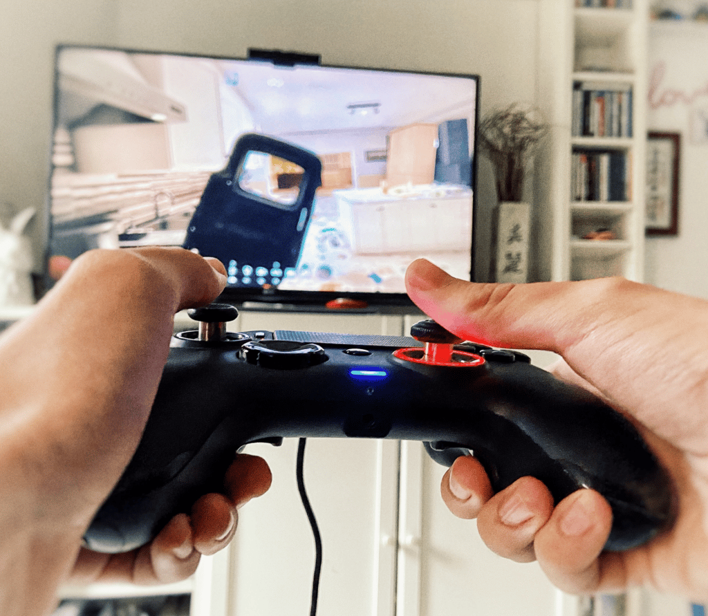 Man aiming a PlayStation controller at a big screen TV