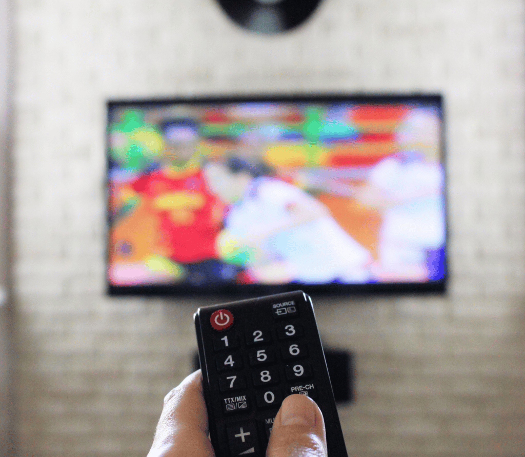 Man watching sports on streaming TV points remote