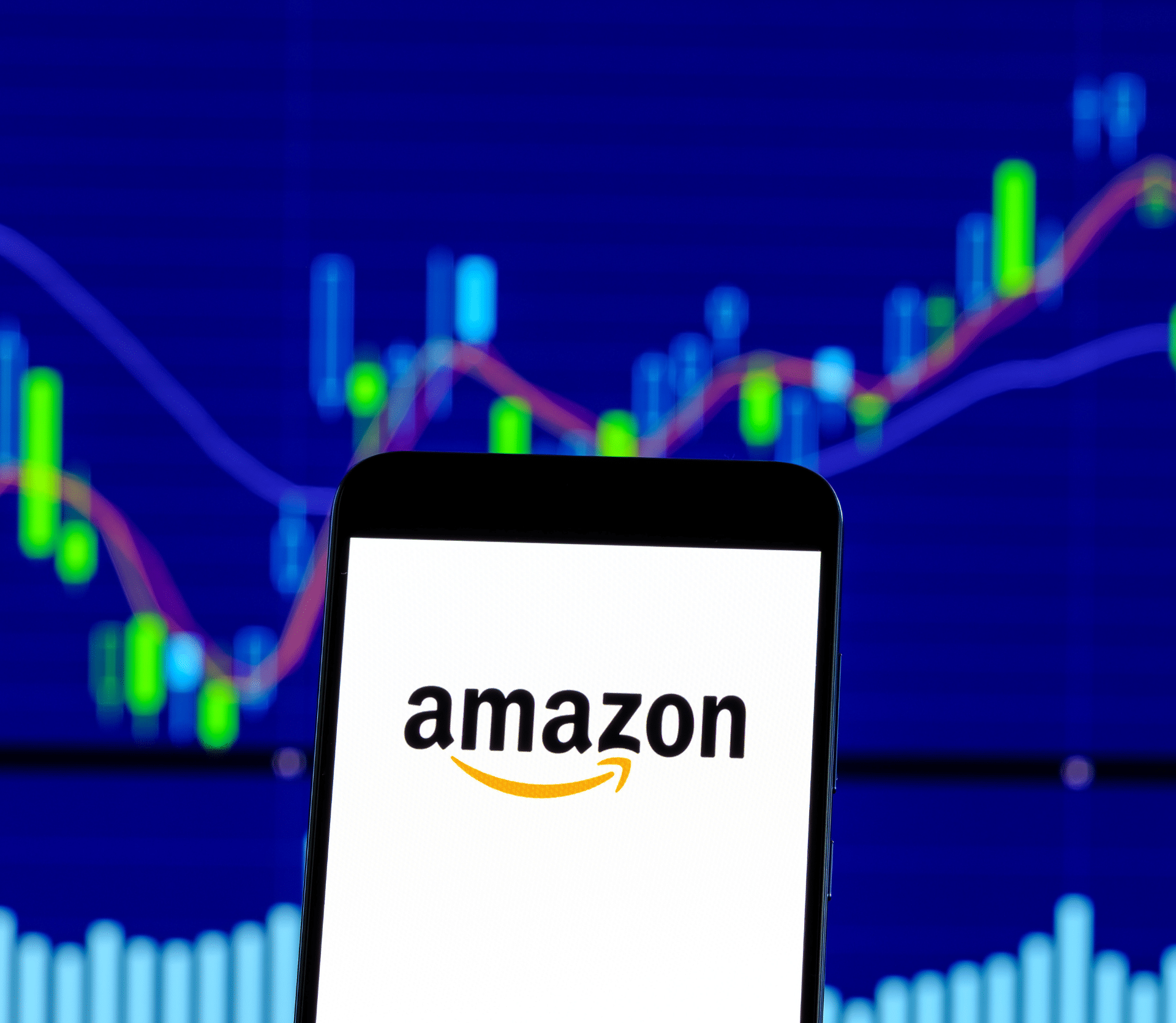 Amazon logo displayed on smartphone with stock market graph in the background