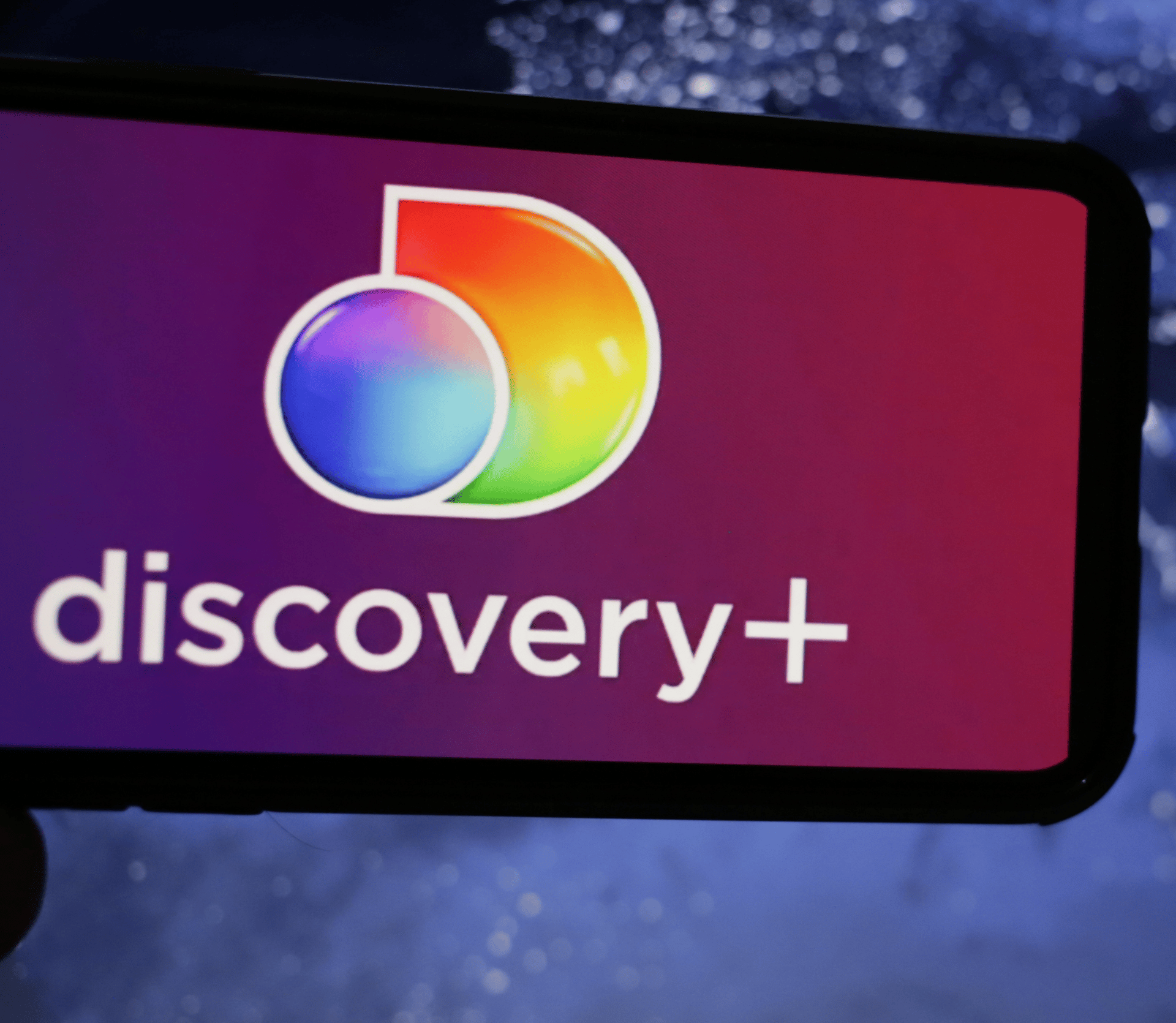 Discovery Plus logo displayed on smartphone on purple background