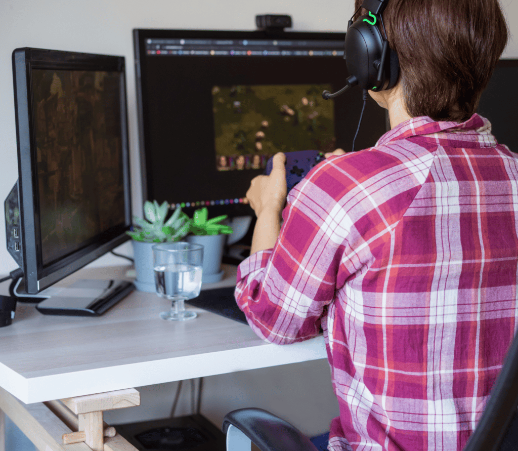 Woman playing Xbox for PC on two monitors