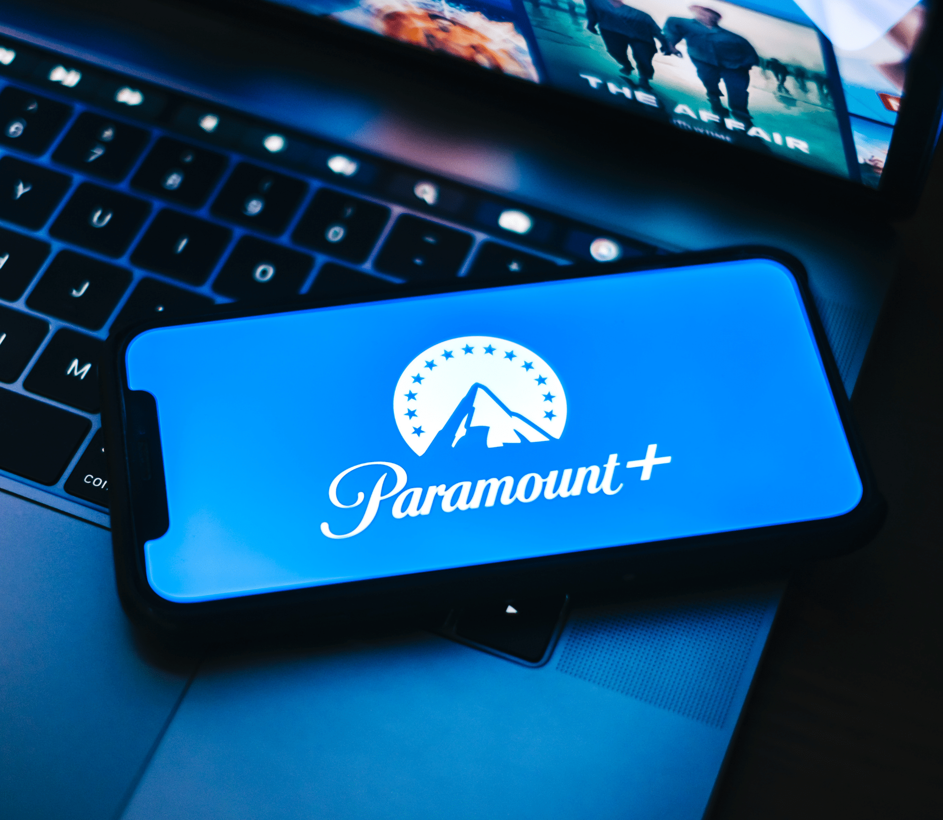 Paramount+ logo displayed on a smartphone on top of a laptop.