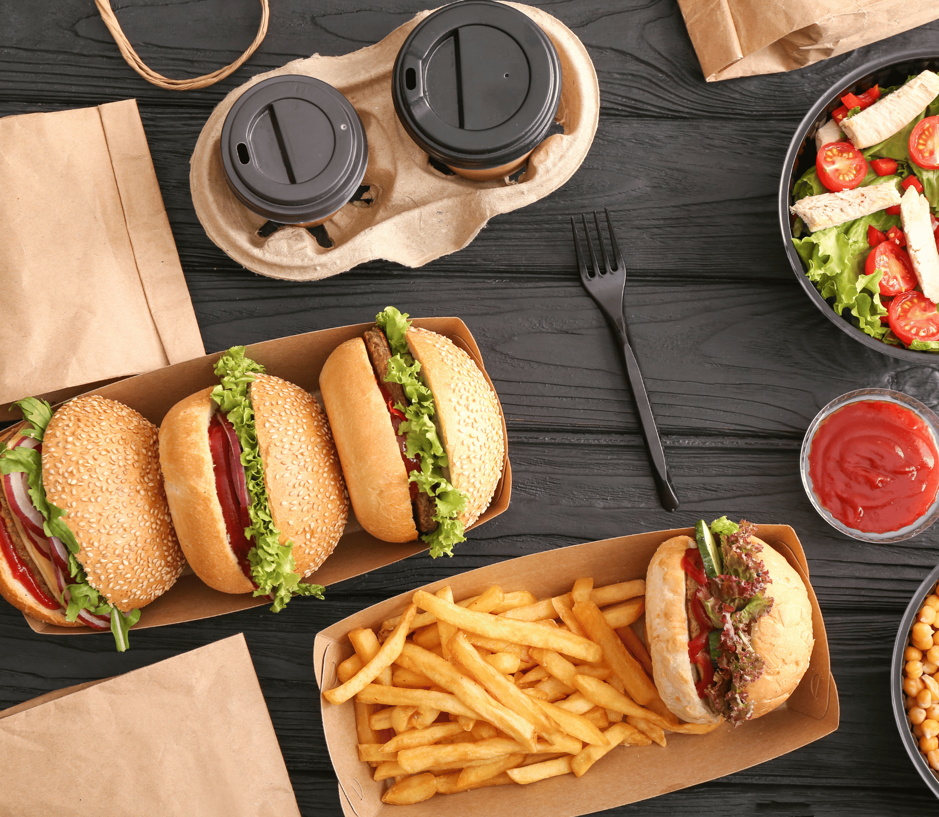 An assortment of takeout food displayed on a wooden table with drinks