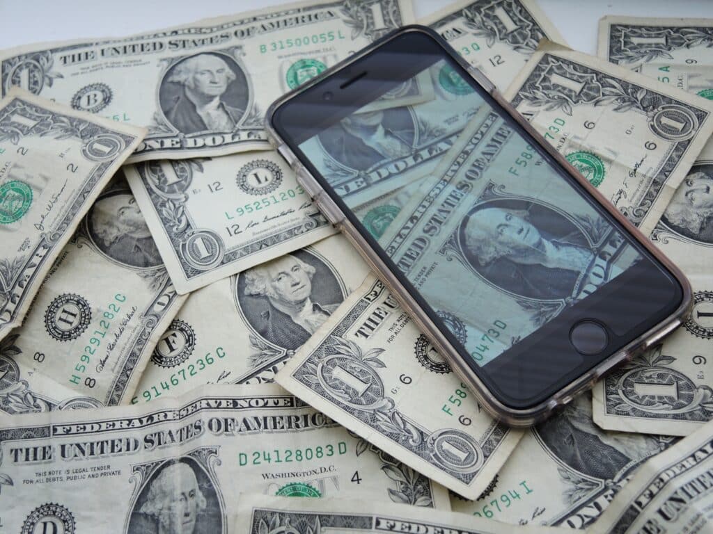 iPhone lying on top of dollar bills, signifying subscription price increases.