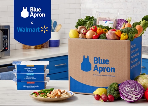 Image of Blue Apron-branded box, filled with ingredients, sitting on kitchen counter next with raw ingredients for meal kits and prepaped meals, featuring Blue Apron and Walmart logos