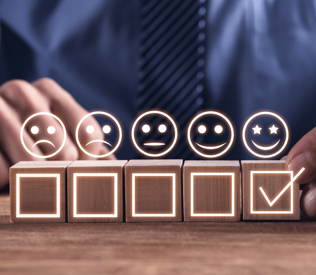 5 wooden blocks, each expressing a different level of customer satisfaction, starting with a frownie face on the left and ending with a smiley face with starry eyes on the right