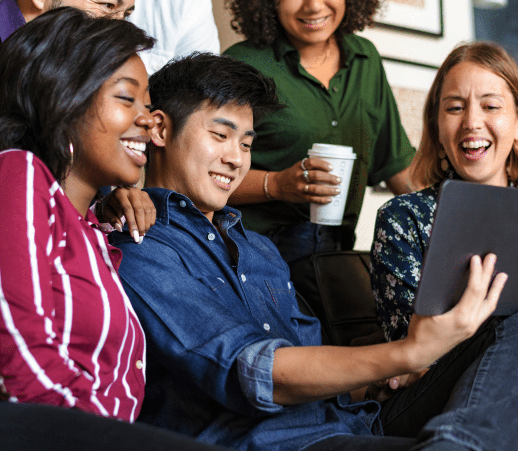 A group of smiling friends watching streaming video on a tablet.