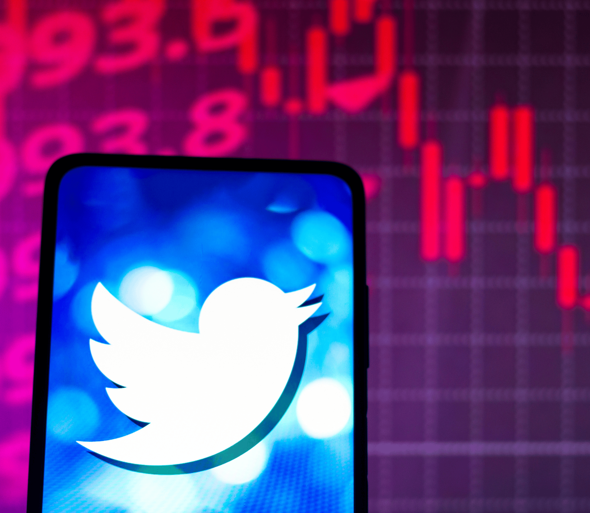 Twitter logo on smartphone with red stock market graph in background