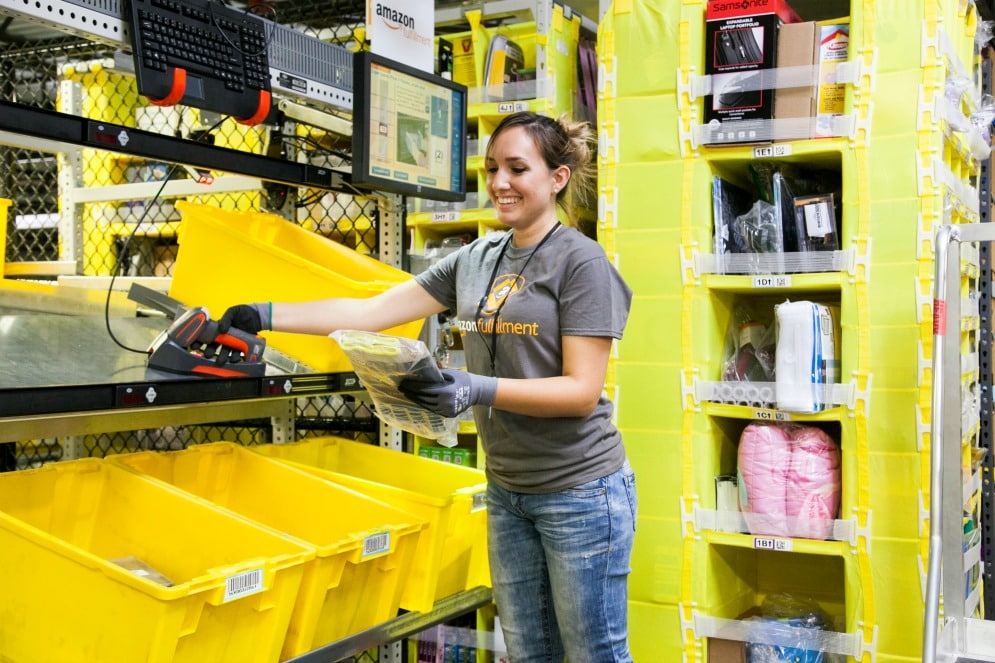 Smiling woman sorts and packs orders in an Amazon Fulfillment Center