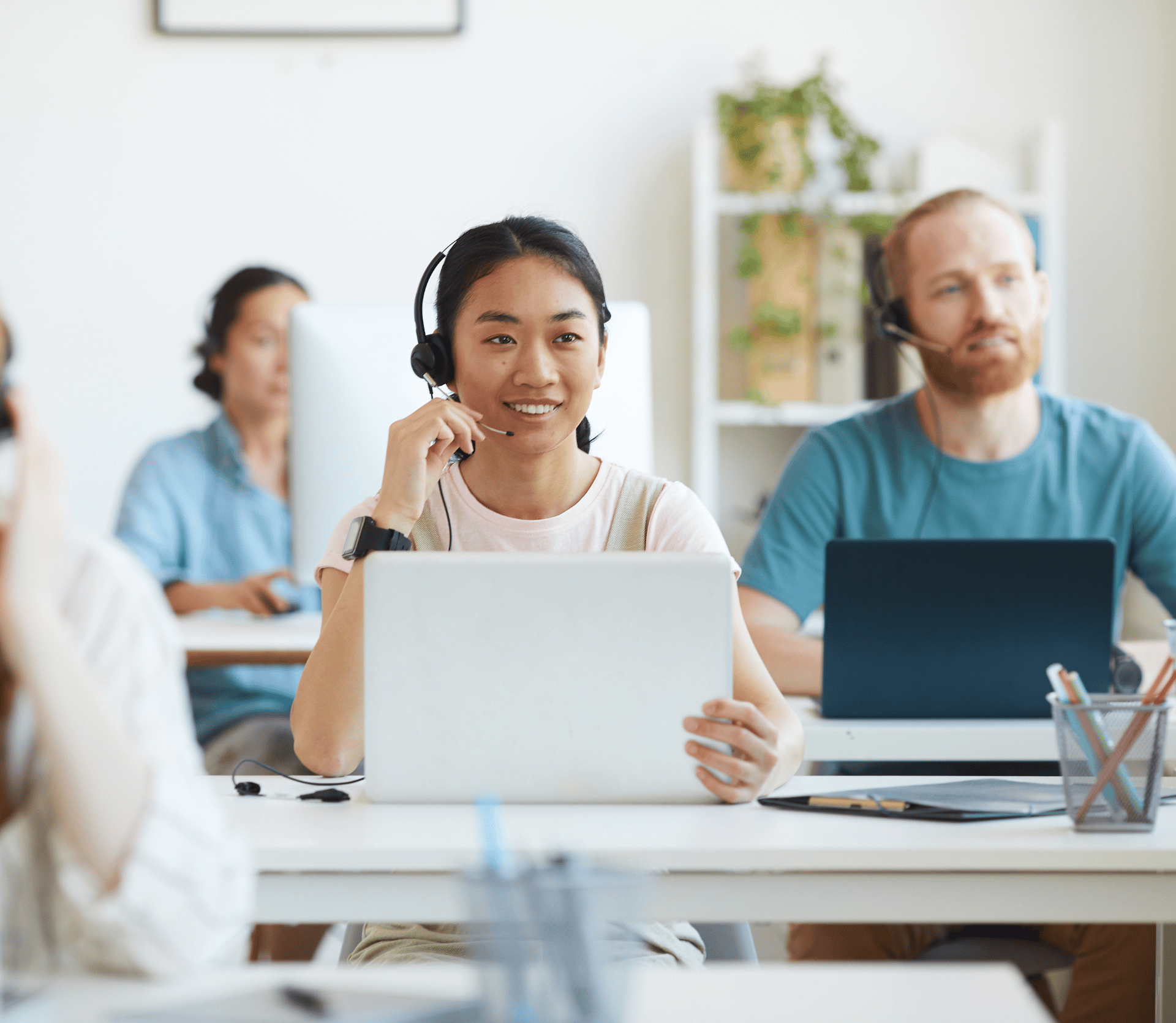 4 customer service reps at their desks talking to customers on headsets