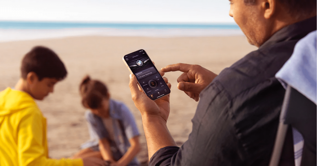 Man using OnStar app while at beach with his two kids.