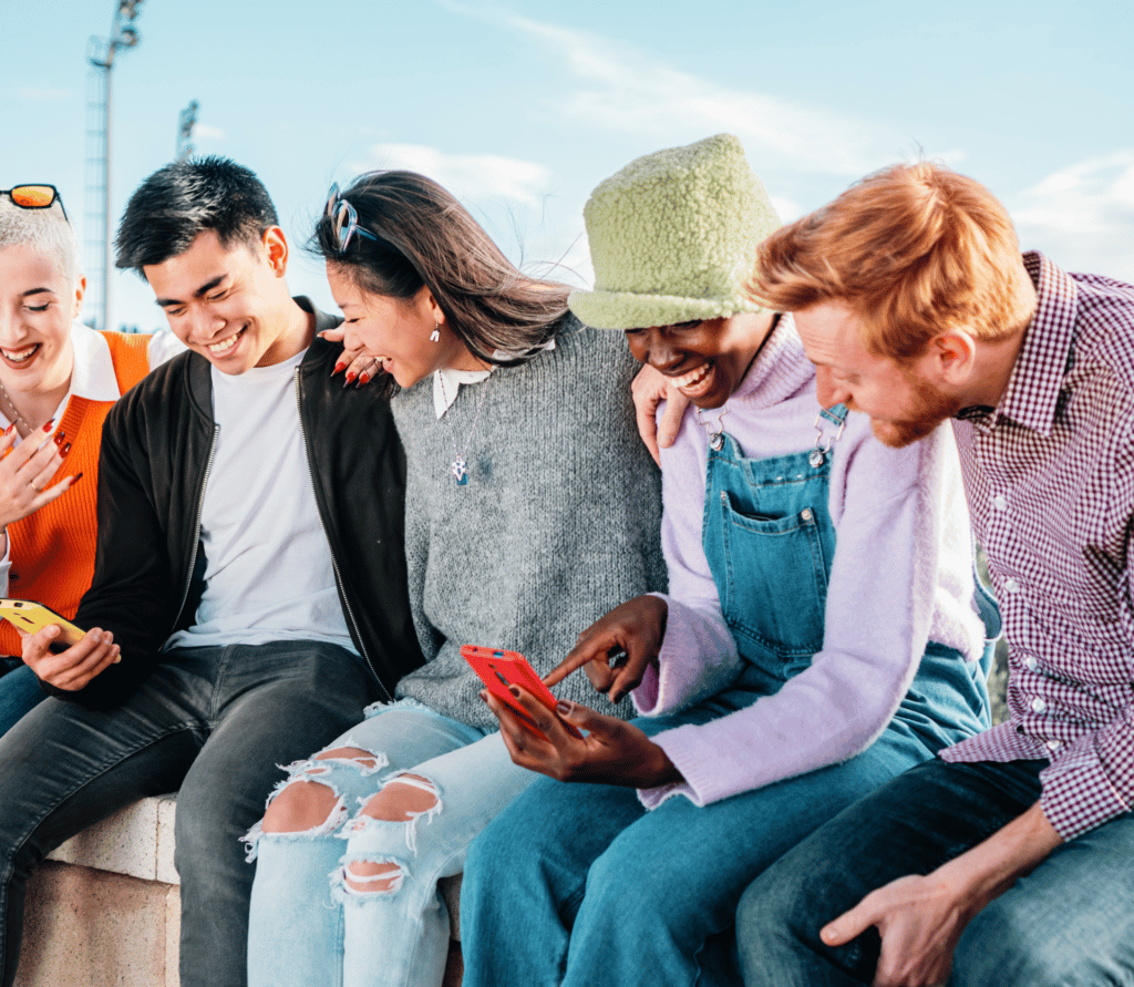 Group of 5 diverse young people looking at social media on their smartphones