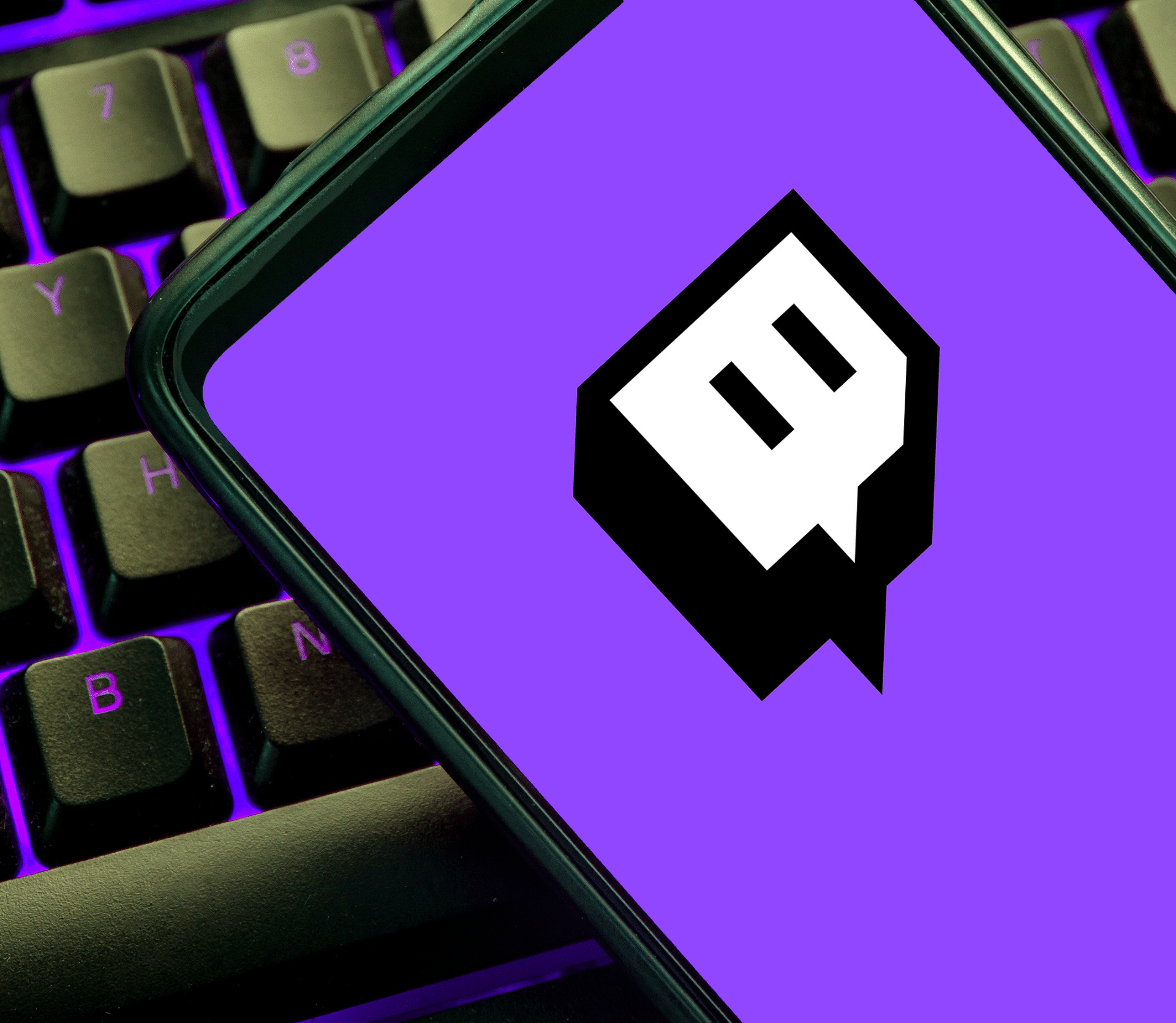 Smartphone with Twitch logo on top of a black keyboard with purple backlighting