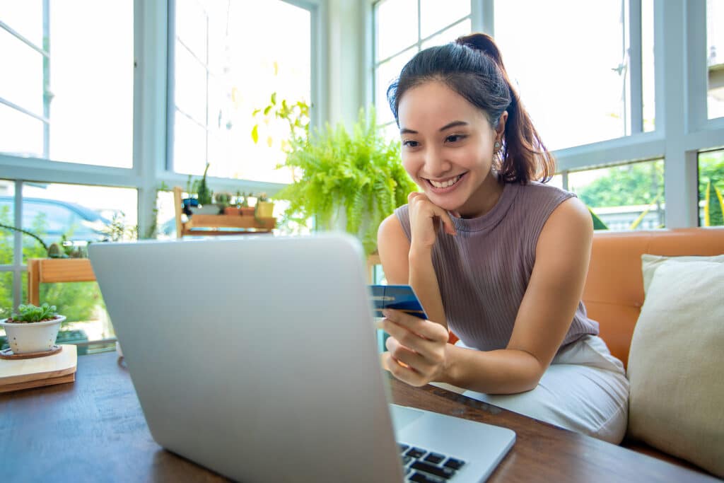 Asian woman is holding credit card and using smartphone shopping online at home. Online shopping  e-commerce  internet banking  spending money  working from home concept