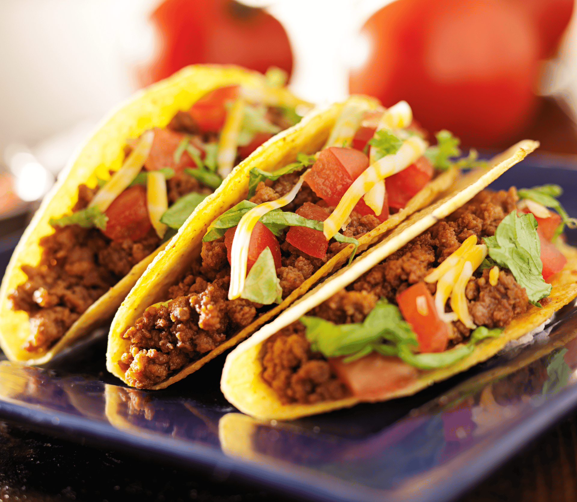 Three hard shell beef tacos displayed on a blue plate