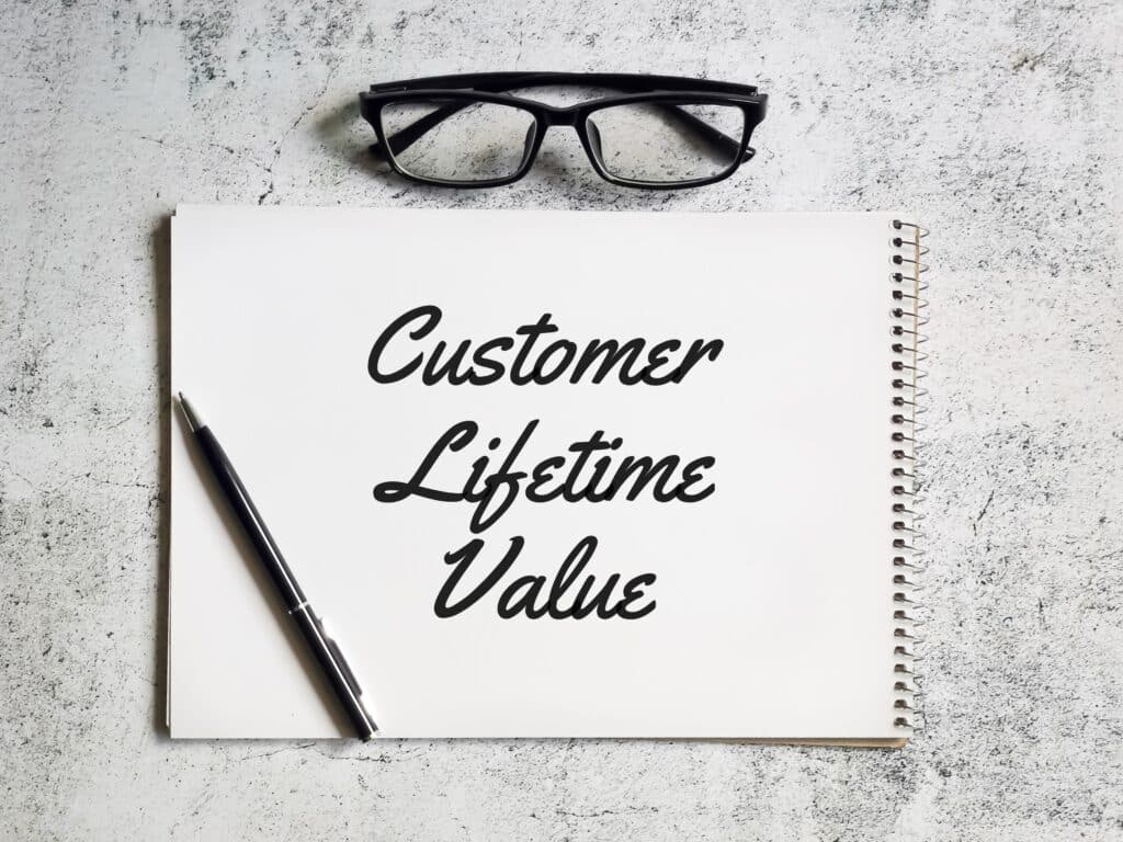 Selective focus notebook written customer lifetime value with pen and eye glasses.