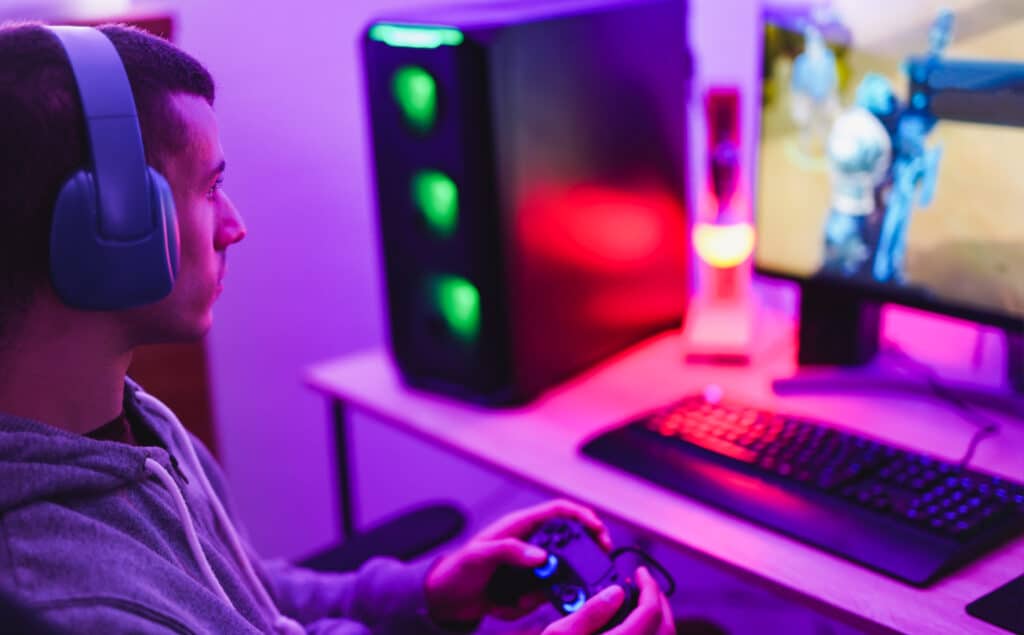 Young man playing video games at home with computer and headphone
