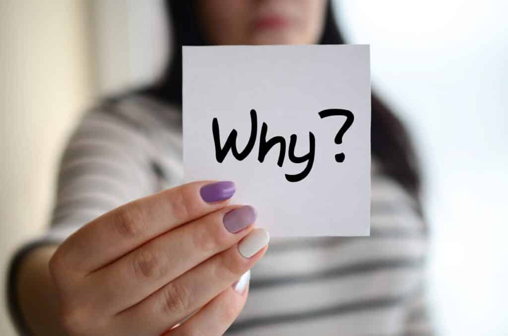 Young sad girl shows a white sticker. Caucasian brunette holding a sheet of paper with message. Why?