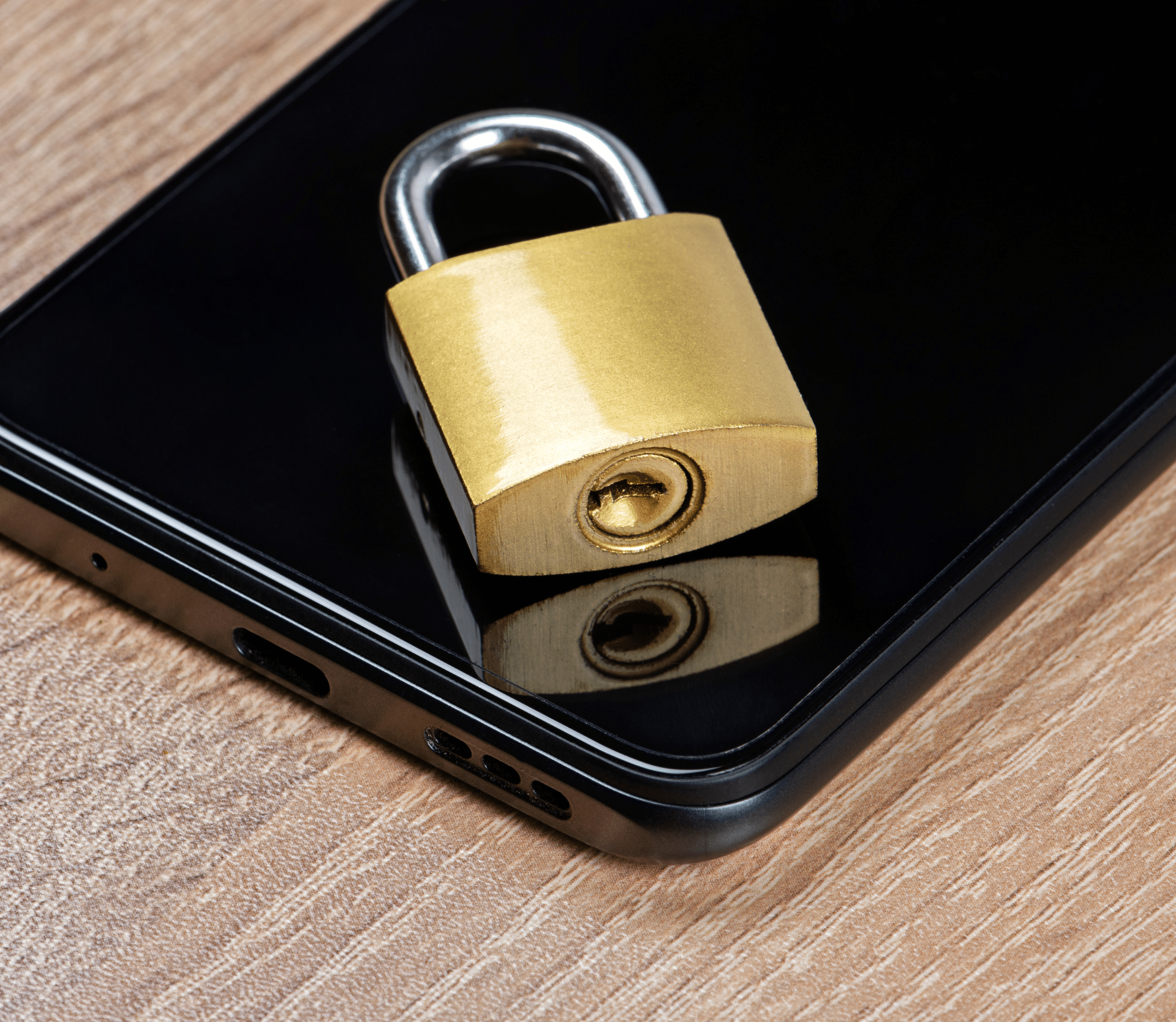 Gold padlock on top of smartphone on desk.