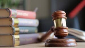 Wooden judge gavel and stack of legal book on table. Laws, legal system and court concept.