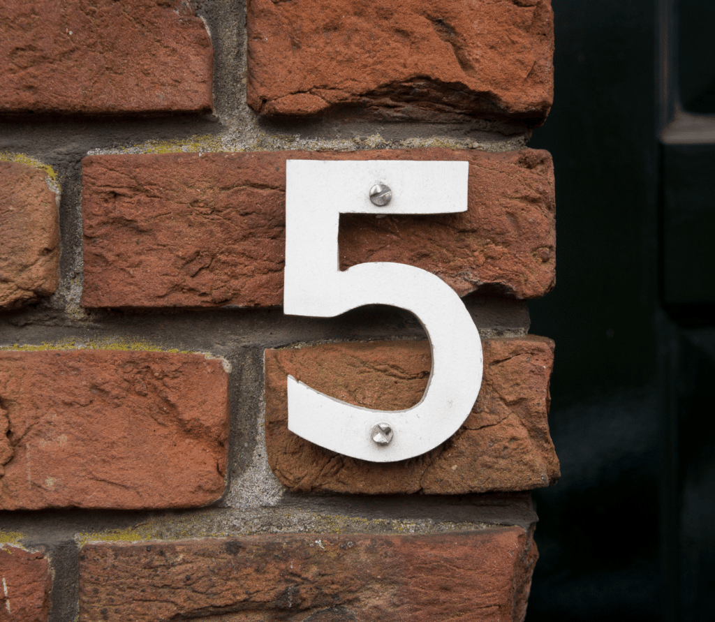 White number 5 screwed into a brick wall