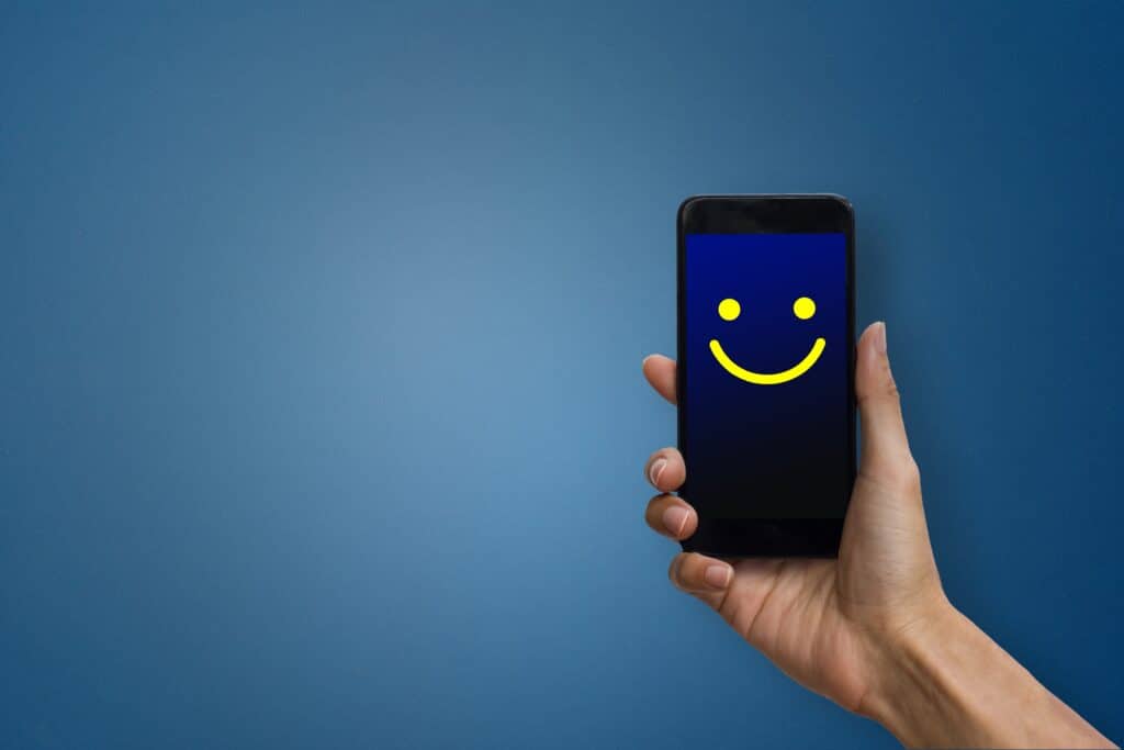 Conceptual the customer responded to the digital survey. The client showing mobile phone screen with happy face. Depicts that customer is very satisfied. Service experience, customer loyalty and satisfaction concept.