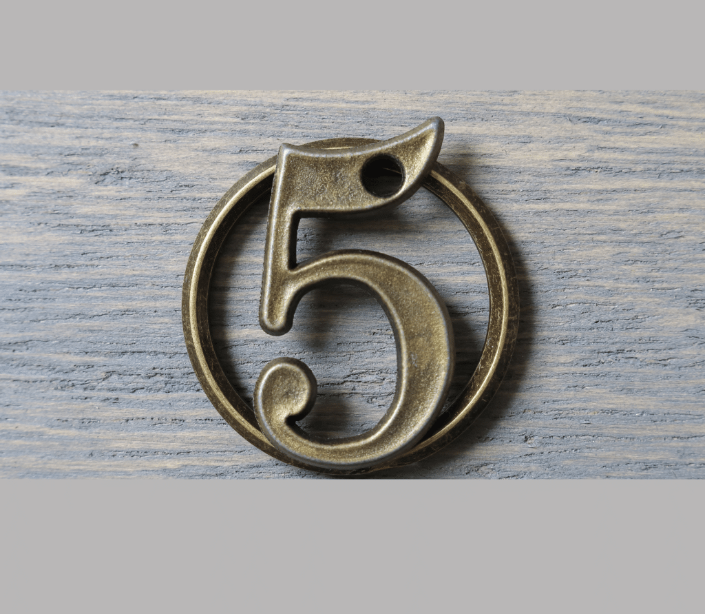 Dark gold, metal five on gray wodden background