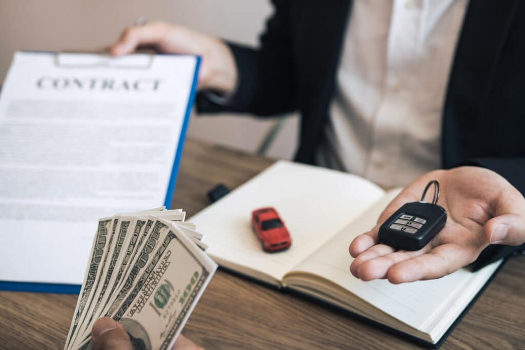 New car buyers are holding cash and handing it to car salespeople while filing a new car signing contract for car buyers.