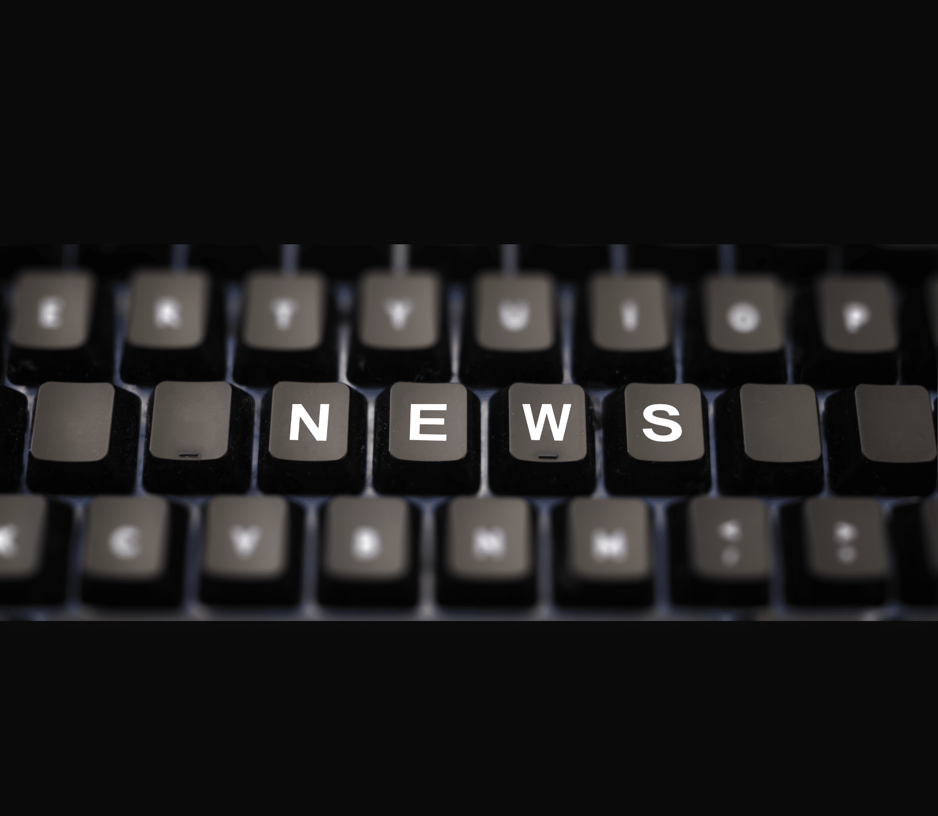 NEWS typed out on a black keyboard on a black background