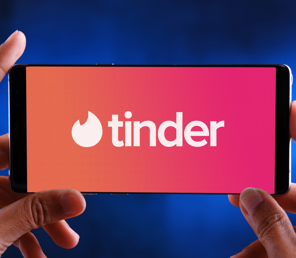 Man holding smartphone with Tinder name and logo