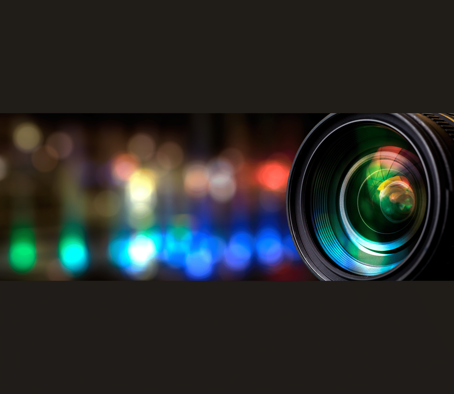 Camera lens on dark background with multicolored reflections to the left