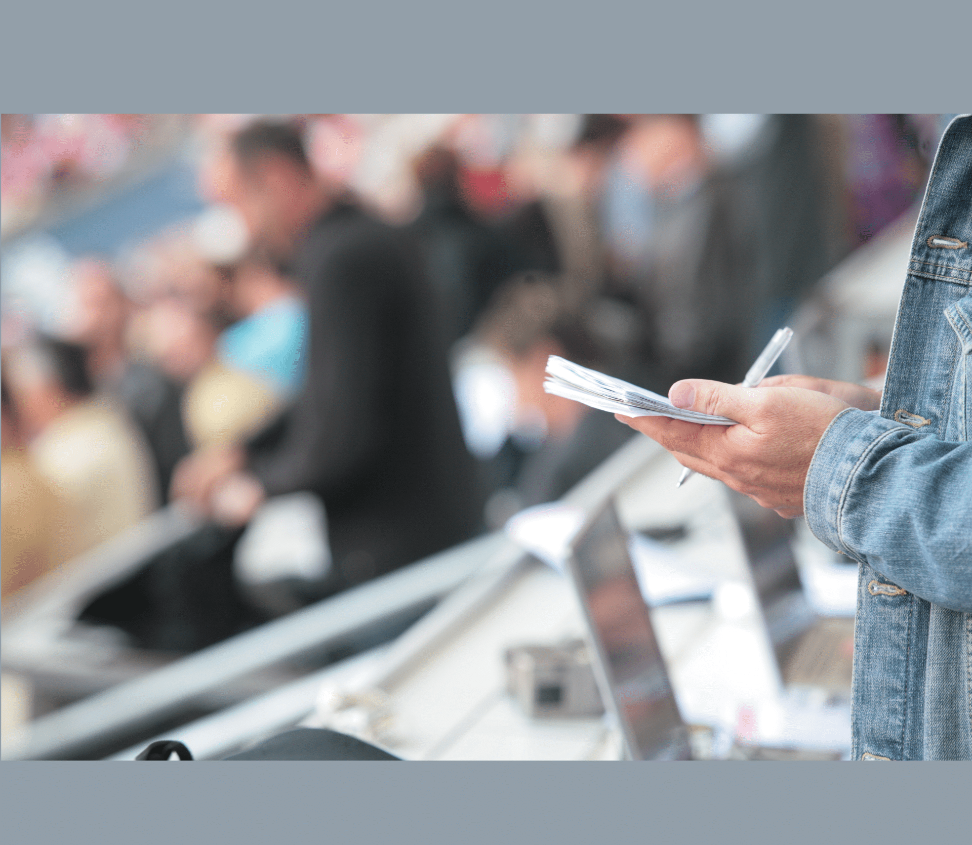 Reporter wearing denim jacket writing notes at a ball game.