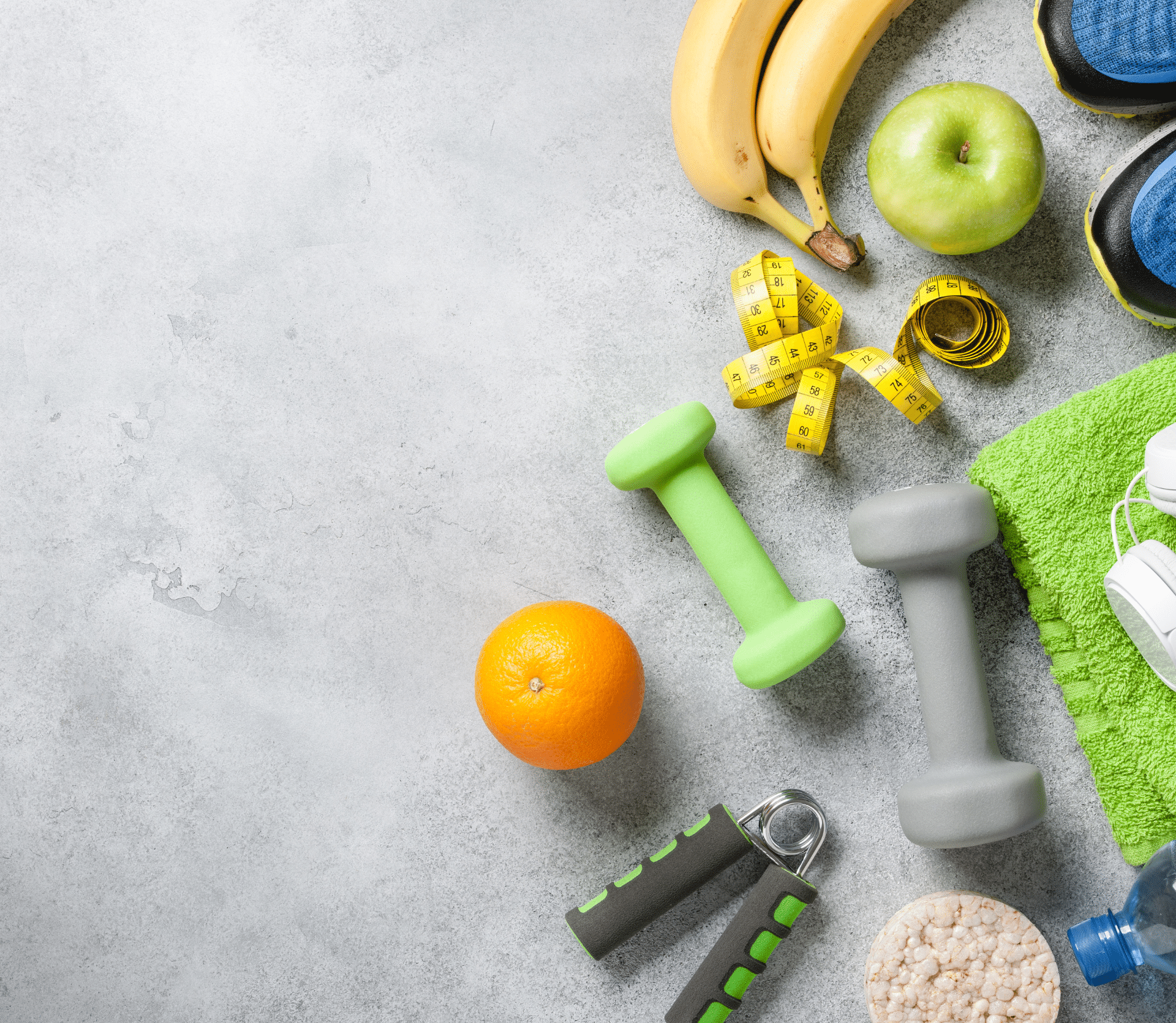 Gray background with weight weights, fruit and other items signifying health and wellness