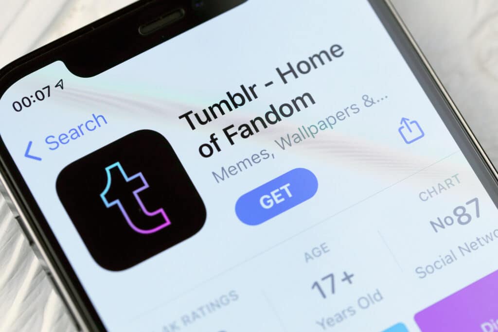 Tumblr icon and application from App store on iPhone 12 pro display screen on white wooden table