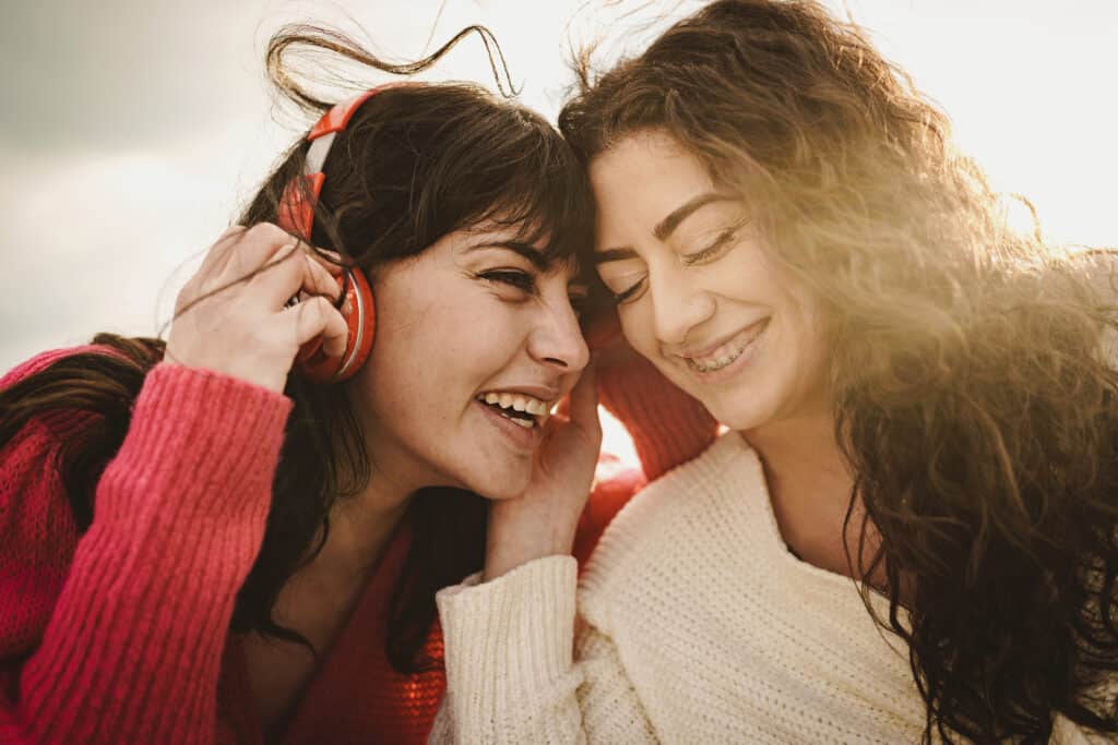 Two young women listening to Amazon Music Unlimited through headphones outdoors