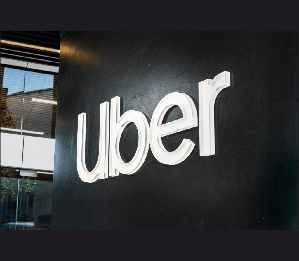 White Uber logo on black sign in front of an office building